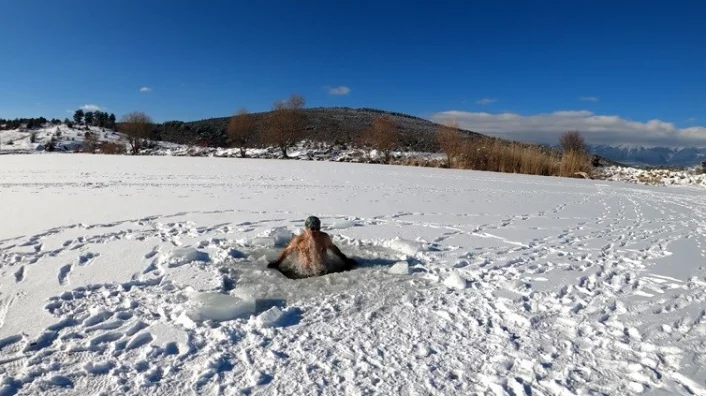 Bursalı dağcı üzerinde yürüdüğü buz tutan göleti testere ile kesip içinde yüzüyor